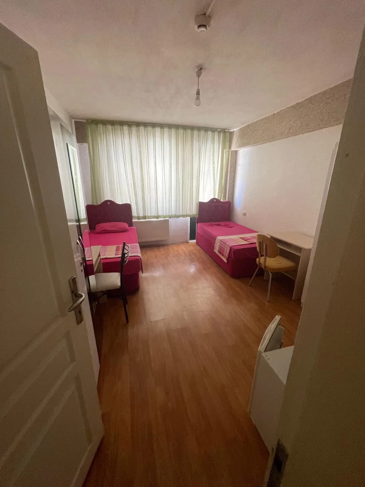 Elit Konaklama'da iki yatak, çalışma masaları ve dolap bulunan çift kişilik oda